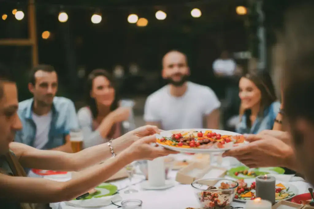 A group of people passing food around a dinner table.