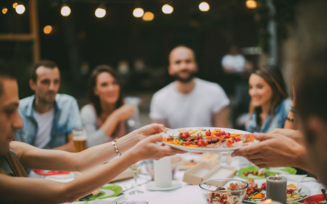 A group of people passing food around a dinner table.