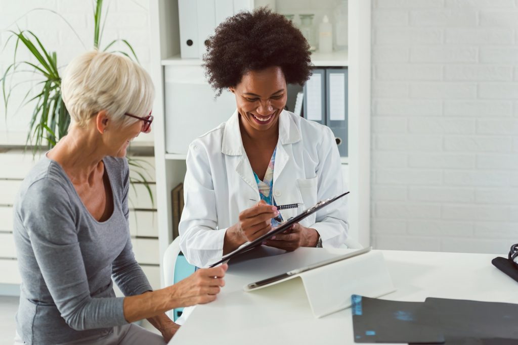 A doctor and patient smiling at a table and looking over records.