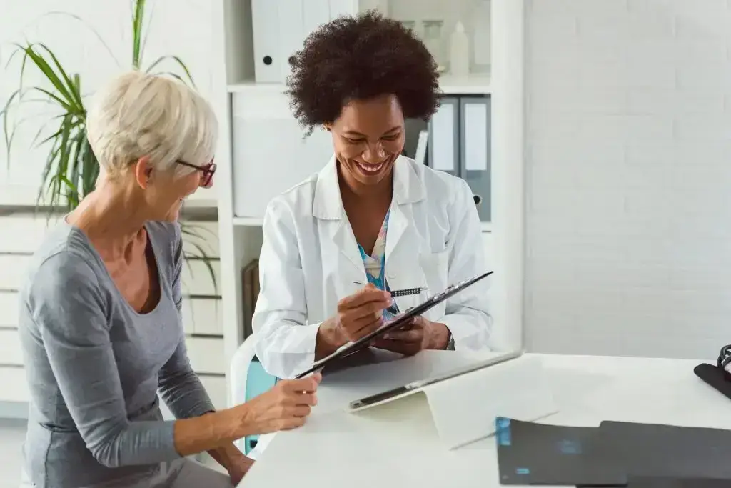 A doctor and patient smiling at a table and looking over records.