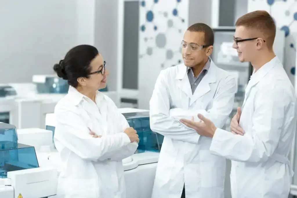 A female scientist speaking to two male scientists in a clinical lab.
