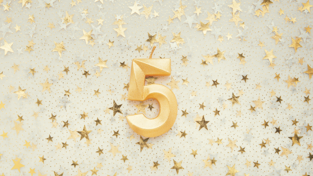 A golden 5 candle on top of a gold and silver star background.