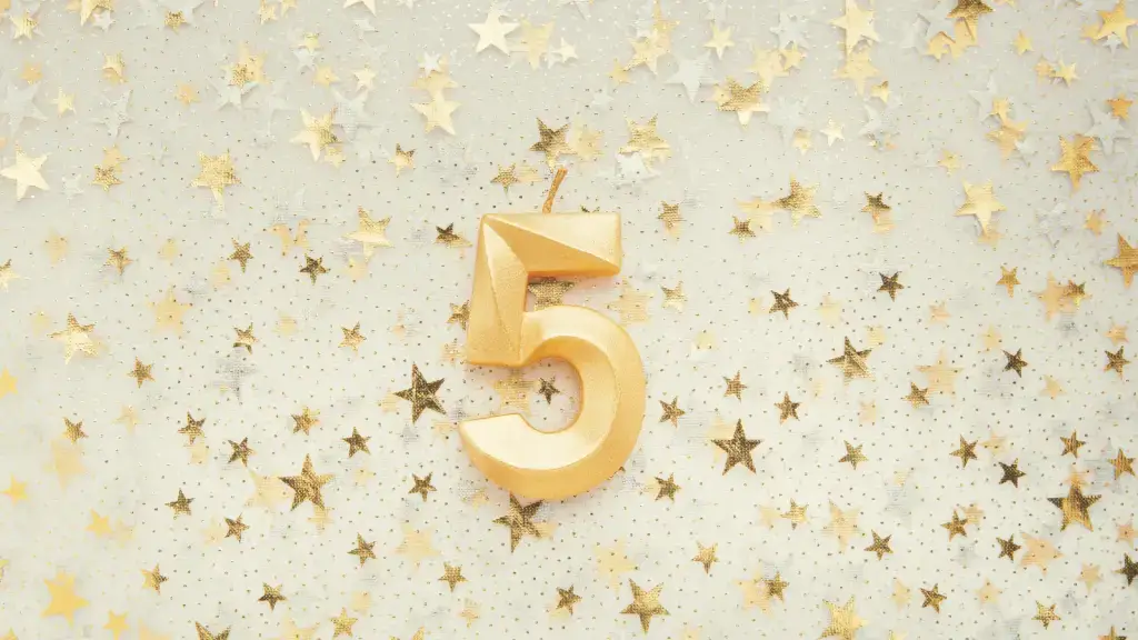 A golden 5 candle on top of a gold and silver star background.