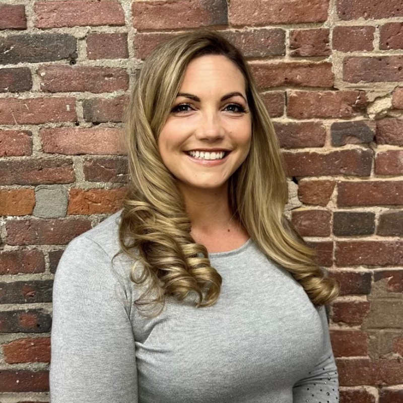 Our Business Development Manager Christi Unger smiling in front of a brick wall.