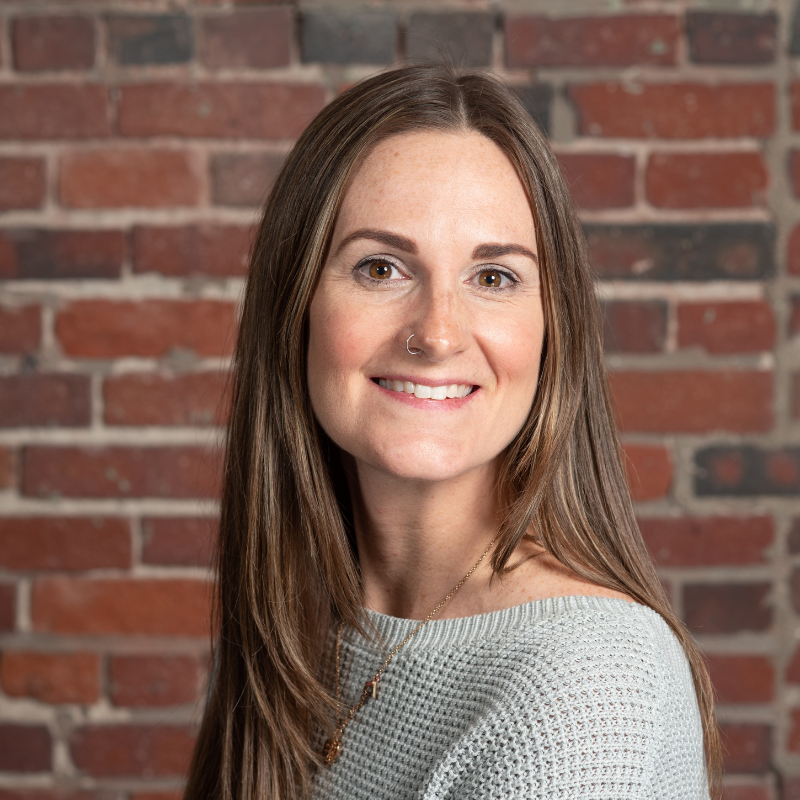 A photo of Noelle Hurley Marketing Communications Manager in front of a brick wall.