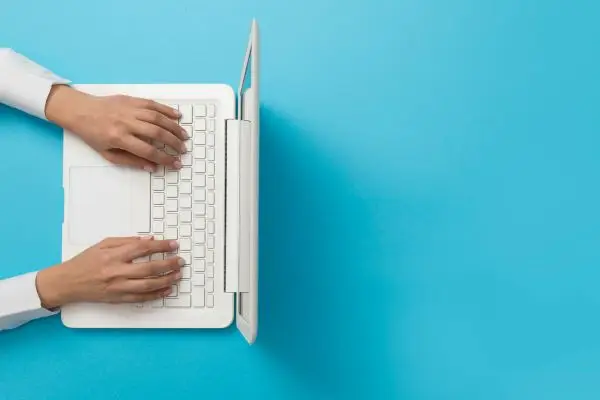 Hands typing on white laptop
