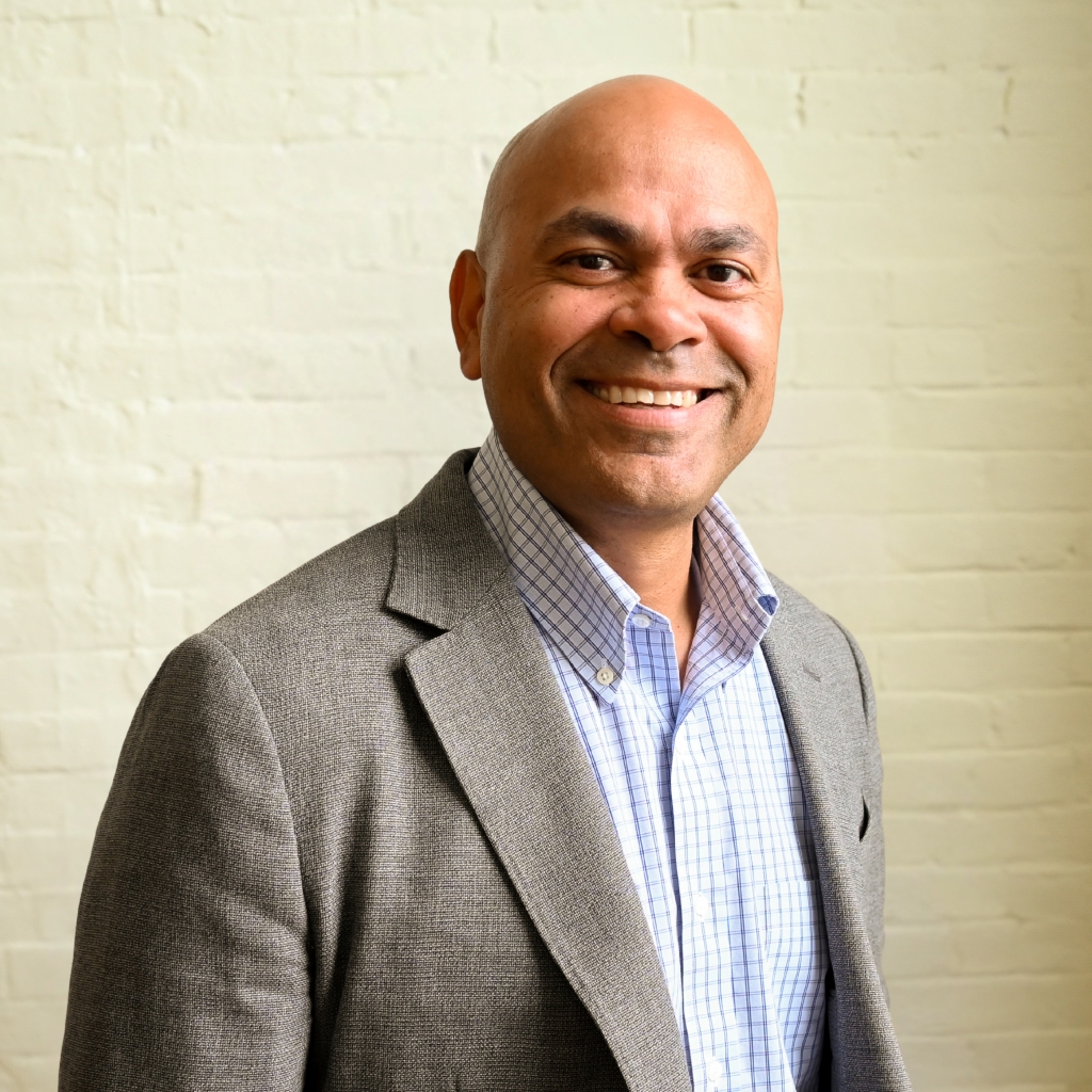 Antonio O'Ferral, Regional Sales Director NE & SW at Immundiagnostik, Inc., smiling in front of a white brick wall.