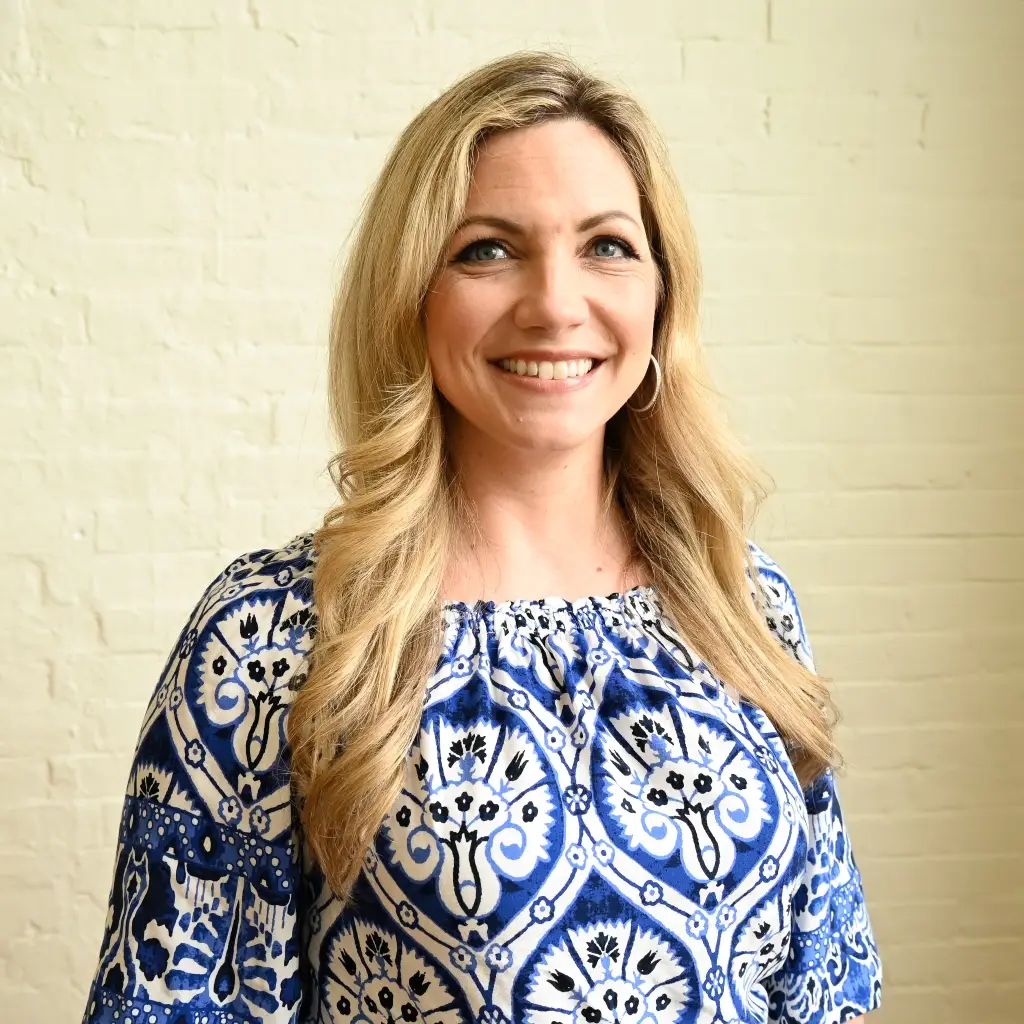 Christi Unger, Commercial Product Manager at Immundiagnostik, Inc., smiling in front of a white brick wall.